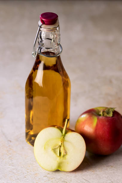 istock Glass Bottle with Apple Vinegar and Apple on Concrete Background Vertical Raw Red Apples 1411975245