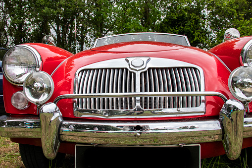 Front view of a grille and headlights of a classic English convertible car