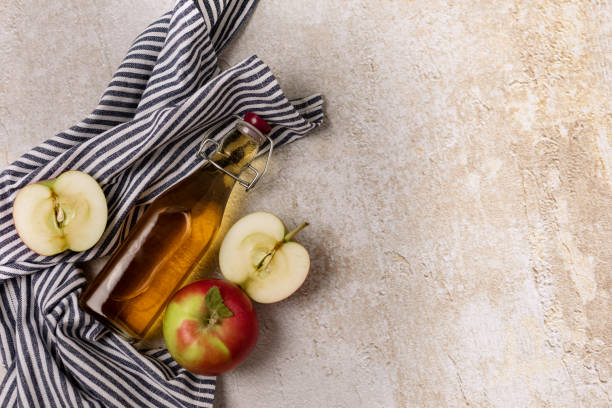 bottle of apple cider vinegar or apple juice with a fresh apple napkin concrete background top view copy space - slenderize imagens e fotografias de stock