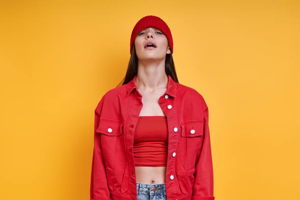 istock Playful young woman in red hat and looking at camera while standing against colored background 1411976499