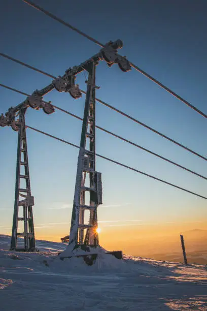 Morning sunrise on Mount Ochodzita in the Beskydy mountains in Poland. Electric wires under the freezing frost and snow cover.