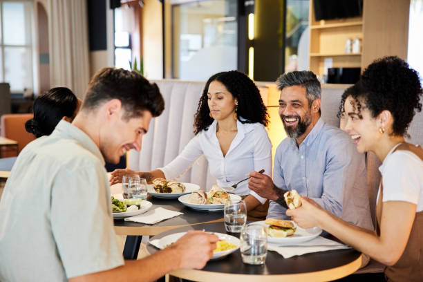 istock Businesspeople laughing while eating lunch in an office cafeteria 1411981164