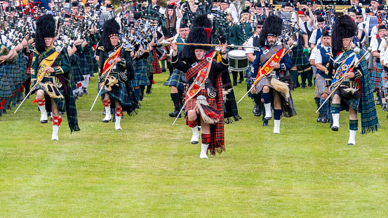 A row of Scottish bagpipers seen from the waist down show off their traditional Scottish men's attire.