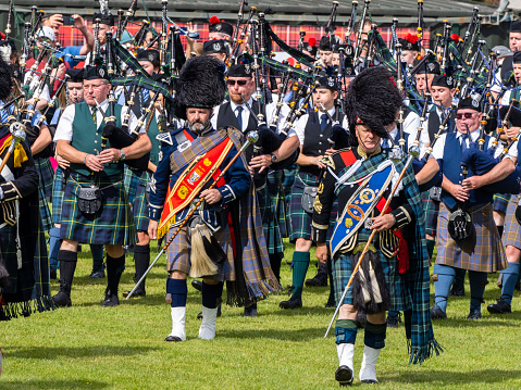 Dufftown, Scotland, UK - July 30, 2022: Drum Majors leading the Massed Pipe Bands at Dufftown Highland Games, Scotland. Massed pipe bands, where a number of smaller pipe bands march together playing traditional tunes on bagpipes and drums, are a feature at Highland Games held in Scotland during the summer, which are a part of Scottish culture and a popular day out for both tourists and local people alike.