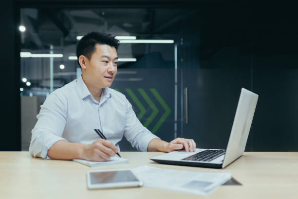 istock Young businessman, freelancer, Asian working with documents, writing with a pen, working on a laptop 1411984273