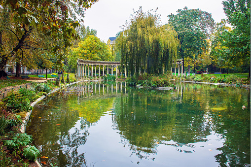 Park Monceau  -  beautyful  Gardening, , late October - artificial ancient colonnade and amazing willow tree with orange leaves. With yellow  and orange leabes - autumn beginning in Paris