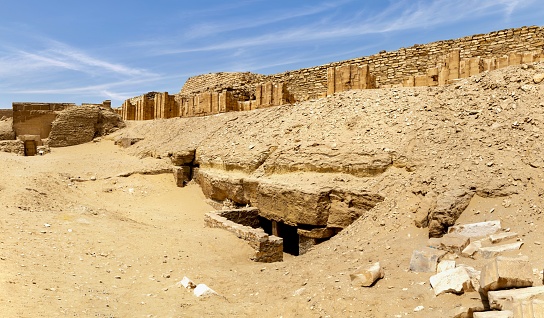 Saqqara, Egypt, April 17, 2022: View of a ruined wall in Saqqara necropolis on a sunny spring day. Saqqara contains the oldest complete stone building complex known in history, including the Pyramid of Djoser (not pictured).