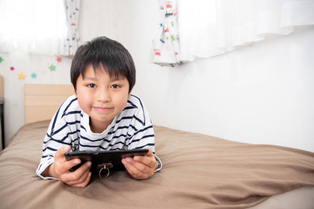 istock Asian boy looking at tablet device in bed 1411991122