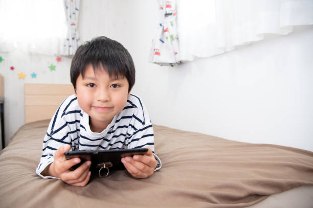 istock Asian boy looking at tablet device in bed 1411991123