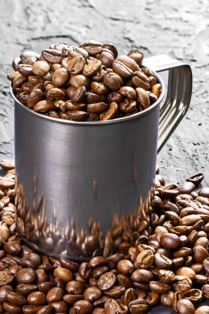 istock Roasted coffee beans in metal cup on a black background.Copy space. Vertical orientation 1411991257