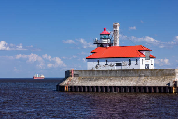 A breakwater lighthouse on Lake Superior with a ship in the background.