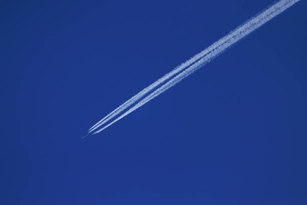 Vapor trails from a large aircraft against a blue sky.