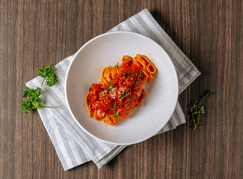 Amatriciana alla Spaghetti, pasta with tomato sauce tomatoes, and pecorino cheese. Italian healthy food in white plate on dark wooden table top view