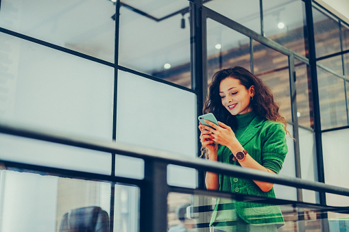 Young businesswoman at work using smartphone