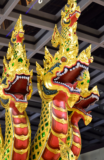 Bangkok, Thailand: Bangkok Airport / Suvarnabhumi Airport - three golden heads - naga is a snake being or a snake deity in Indian and Buddhist mythology. Nagas are known as beings with magical abilities and can assume human form at any time. Occasionally they are said to leave their kingdom and mingle with humans. They are regarded as guardians of transitions, thresholds and doors, especially in a symbolic sense. Archenemy of the Nagas is Garuda , the companion animal of Vishnu.