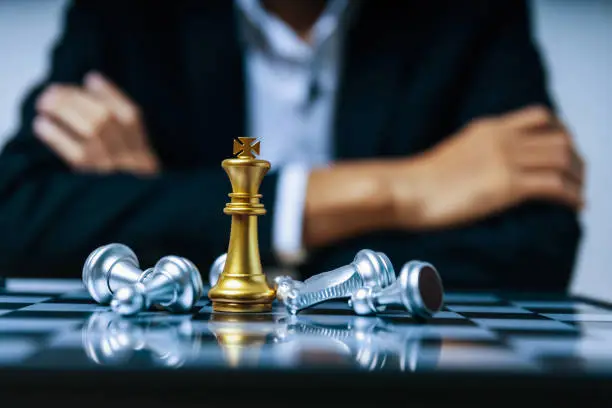 Photo of Team leader. golden king with silver chess piece on chess board game competition on business man background, checkmate, chess battle, victory, success, leadership, teamwork, business strategy concept