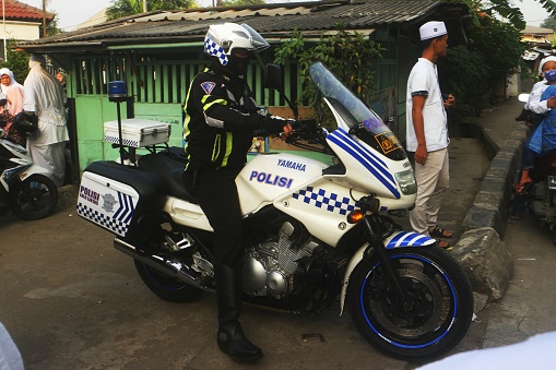 Jakarta, Indonesia - July 30, 2022: A police officer ride a motorcycle to convoy the parade. The Parade is to celebrate Islamic New Year. The Parade was held on Saturday morning.