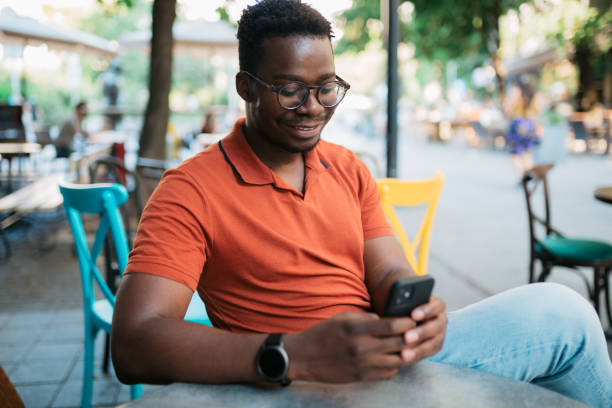 istock Young man sitting in a coffee shop and using a smart phone 1412000103