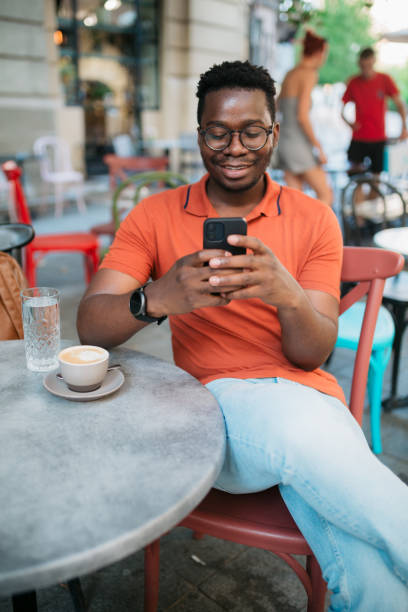 istock Young man sitting in a coffee shop and using a smart phone 1412000106