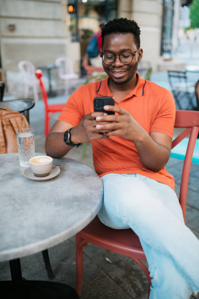 istock Young man sitting in a coffee shop and using a smart phone 1412000107