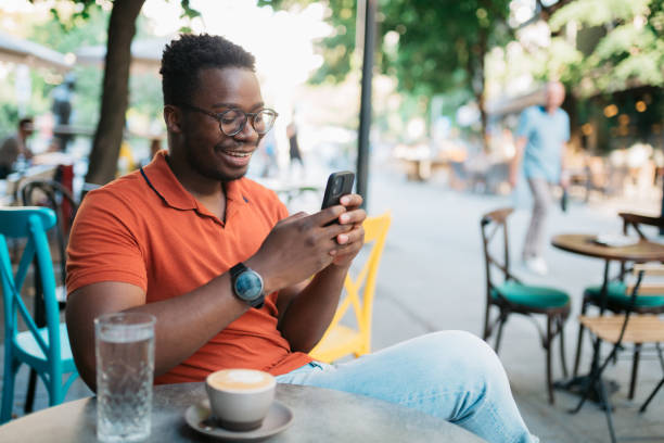 istock Young man sitting in a coffee shop and using a smart phone 1412000116