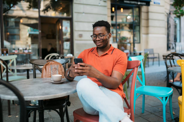 istock Young man sitting in a coffee shop and using a smart phone 1412000632