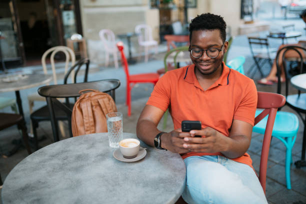 Young man sitting in a coffee shop and using a smart phone stock photo
