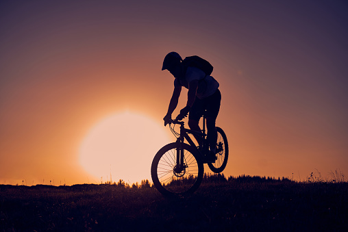 A cyclist riding a bike on a mountain at sunset. High-quality photo