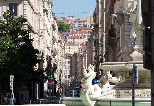 Brest street with the Jacobins fountain in the foreground and the Croix Rousse hill in the background on a hot day in Lyon, France.