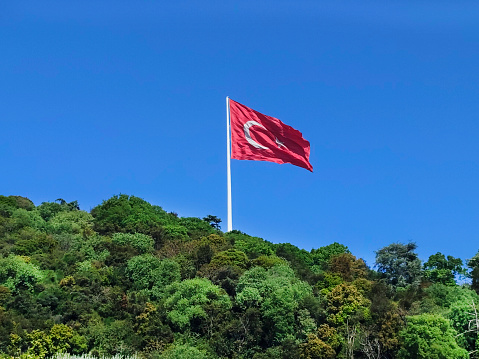 Turkish flag at mountain with clear blue sky.