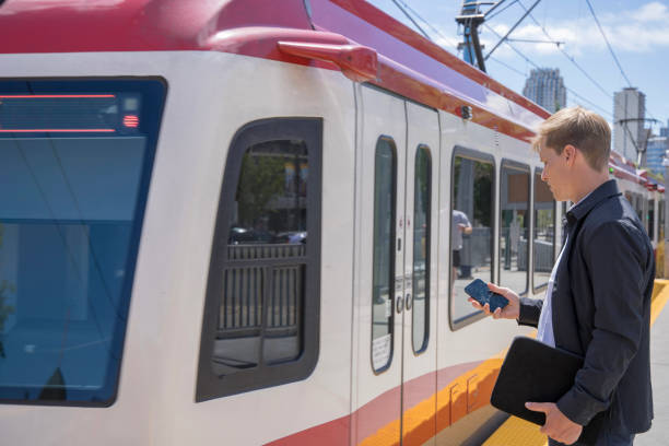 istock Young business executive waits for commuter train, business district distant 1412010939