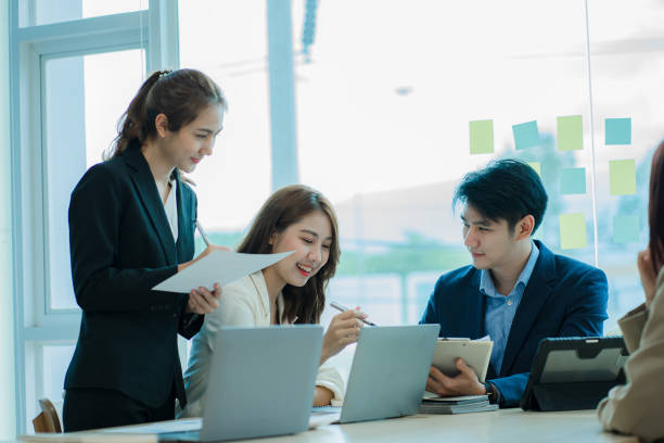 istock Young Asian business team working with laptops on financial documents with happy smiles. Group of business people meeting in a modern office Design and Concept Planning 1412012502