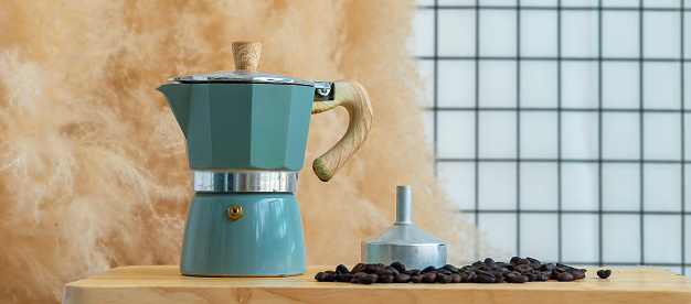 Coffee maker (Moka Pot), Moka pot on a wooden table next to coffee bean with whit background.