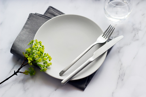 Elegant table setting with empty grey plate, silver cutlery on linen napkin. Table decoration. High quality photo