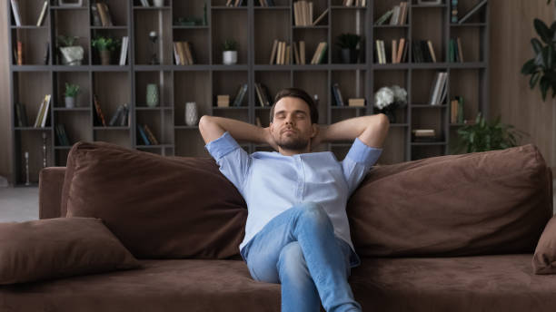 istock Serene man with closed eyes sitting on couch at home 1412021228