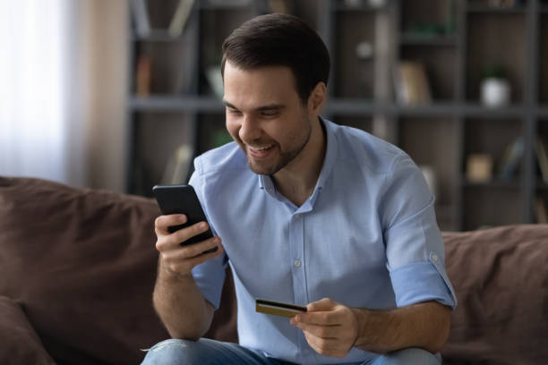 istock Excited man paying by gold credit card online, using smartphone 1412021244