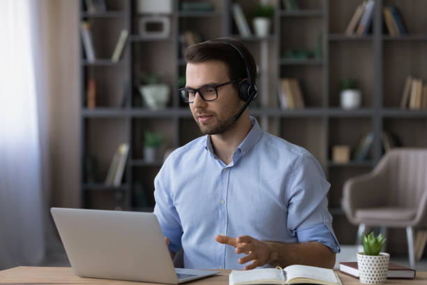 istock Focused businessman in glasses and headset making video call 1412021357