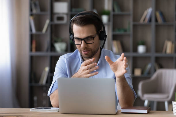 istock Businessman in glasses and headset talking, making video call 1412021369