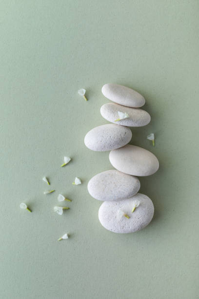istock White stones stack and flowers on green background. Card for meditation, balanced, tranquil, spa concept. Top view. 1412025105