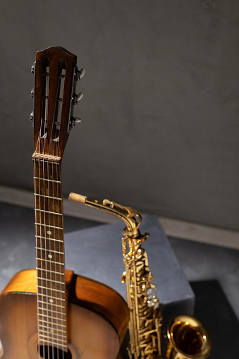 Acoustic guitar and saxophone in studio. Music concept with musical instrument near wall