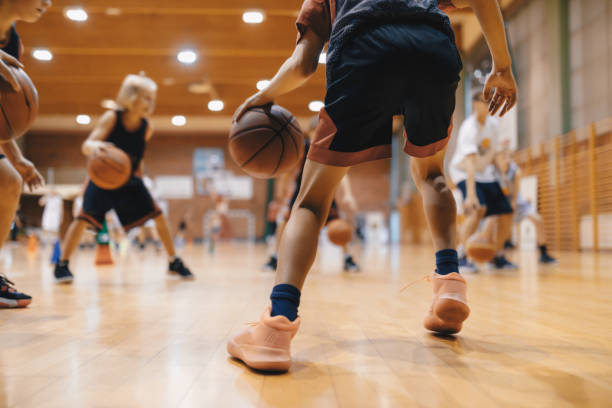 joueur de basket-ball de niveau junior rebondissant au basket-ball. jeune basketteur avec ballon classique. séance d’entraînement de basketball pour les jeunes. cours de sport scolaire - basketball photos et images de collection