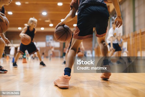 istock Junior level basketball player bouncing basketball. Young basketball player with classic ball. Basketball training session for youth. School sports class 1412026365