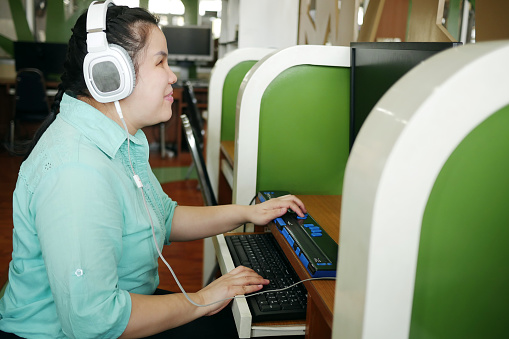 Mujer asiática con discapacidad para la ceguera que utiliza una computadora con pantalla braille actualizable o terminal braille, un dispositivo de asistencia tecnológica para personas con discapacidad visual en el lugar de trabajo. photo