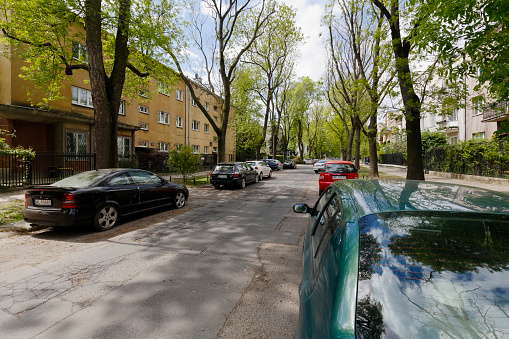 Warsaw, Poland - May 03, 2019: Cars are parked along the street. In the district called Saska Kepa there are residential houses and there are many trees.