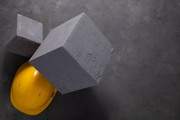 istock Concrete cube and construction helmet on floor background texture. Cement block and hardhat 1412030755