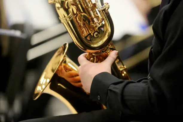 A closeup of the hands of a musician playing a baritone saxophone.