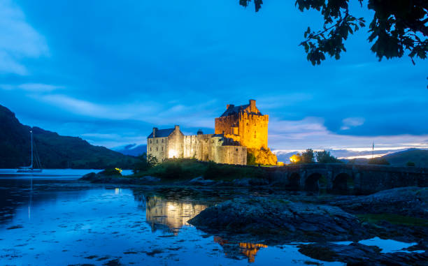 Eilean Donan Castle illuminated in the night Dornie, Scotland, UK, July 19, 2022.  Eilean Donan Castle illuminated in the evening with beautiful lights and reflection in the water. scottish highlands castle stock pictures, royalty-free photos & images