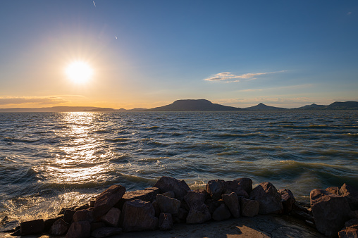 The sun sets over the waves of Lake Balaton, Hungary. Photographed from the pier of the town of Fonyód in northwesterly direction.
