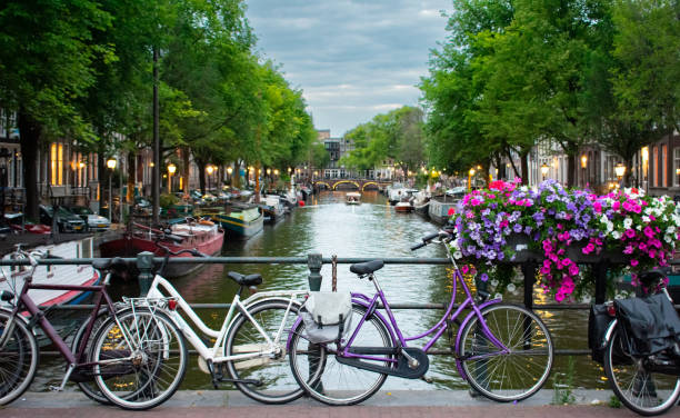 fahren sie bei sonnenuntergang über den kanal in amsterdam. wassertaxi im hintergrund der malerischen stadtlandschaft in den niederlanden mit blick auf den fluss amstel. - amsterdam holland city night stock-fotos und bilder