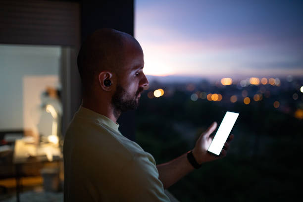 istock Male trader using mobile phone on balcony at his home during dusk hour 1412036356